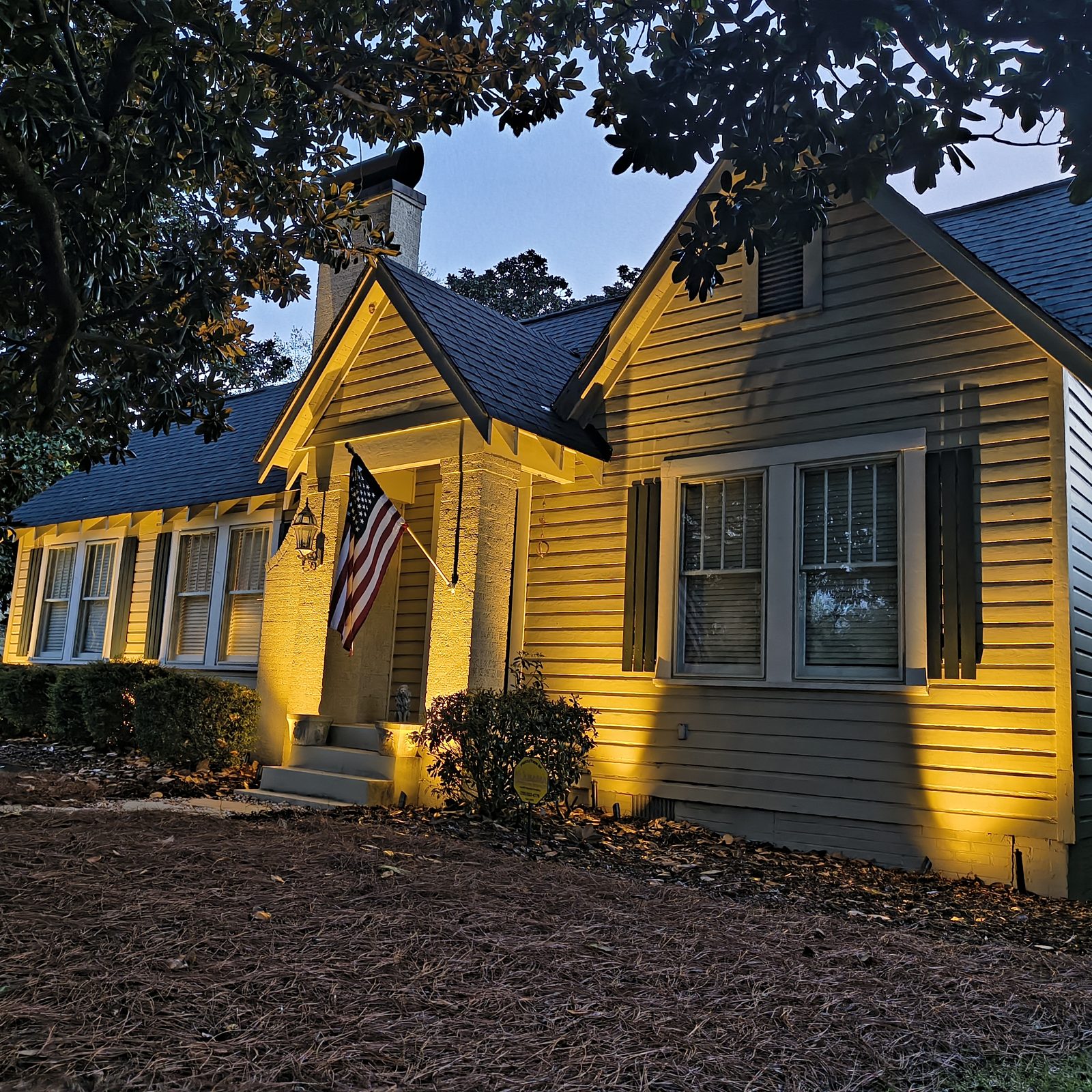 Craftsman home with custom landscape lighting at dusk