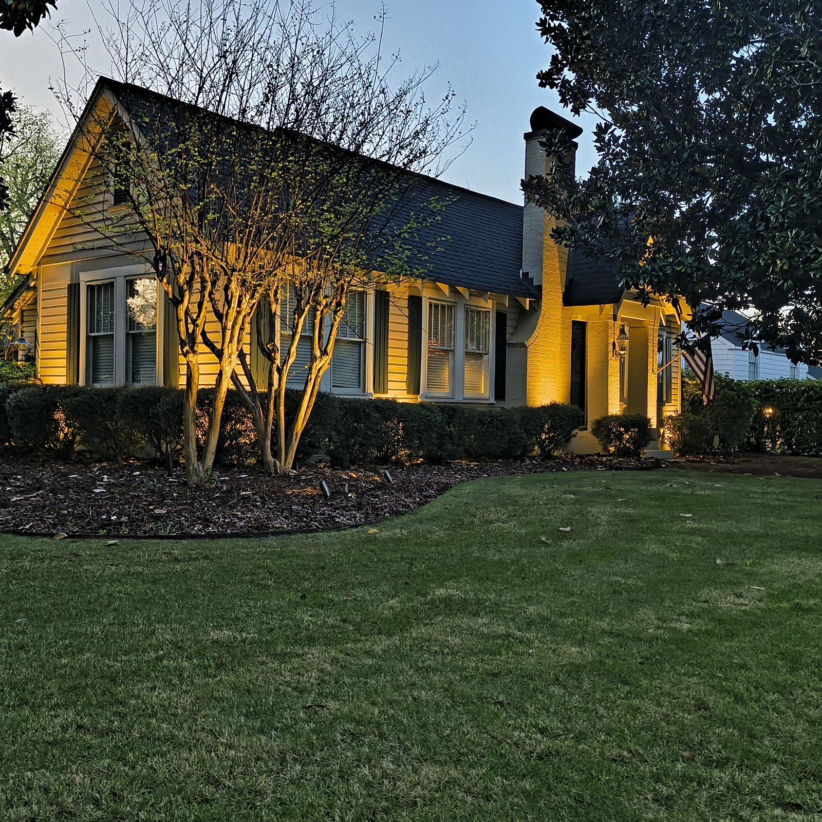 Cottage with warm landscape uplighting